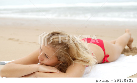Sexy woman in a bikini relaxes on a sandy beach at the ocean 59150305