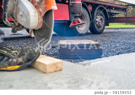 Construction worker at stone cutting work at concrete base by cut-off saw with diamond wheel 59159352