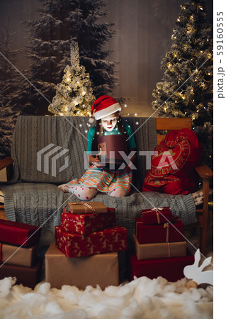 Girl in santa`s hat opening magic box with present 59160555