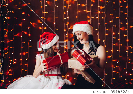 Happy mother with daughter unwrapping Christmas 59162022