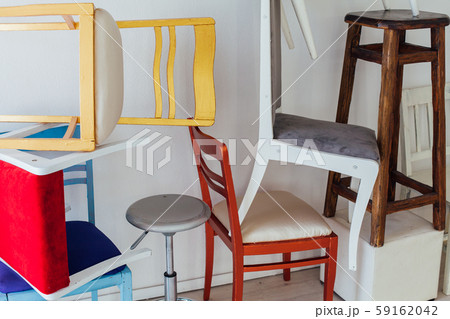 many different chairs of different colors stand at the white wall many different chairs of different colors stand at the white wall 59162042