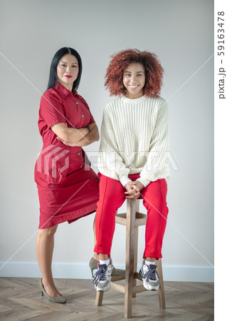 Friends wearing bright clothing standing near white wall 59163478