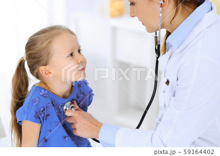 Doctor examining a little girl by stethoscope. Happy smiling child patient at usual medical 59164402