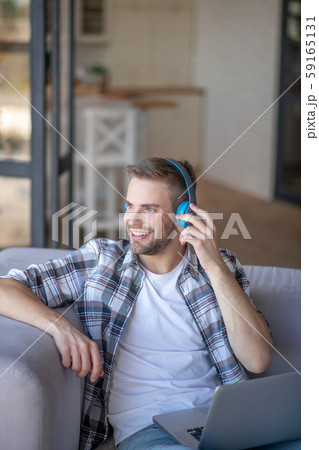 Bearded young man wearing blue headphones smiling 59165131