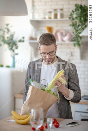 Man taking corn out of bag after going to supermarket Man taking corn out of bag after going to supermarket 59165593