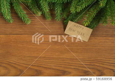 Flat lay christmas background with spruce twigs and happy new year card on ash wood surface Flat lay christmas background with spruce twigs and happy new year card on ash wood surface 59168956