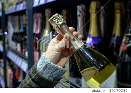 Bottle of champagne in the hands of the buyer in the store 59170252