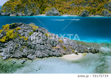 Limestone karst star beach at Matinloc Island with tourist boats in ocean strait in background. El 59170739