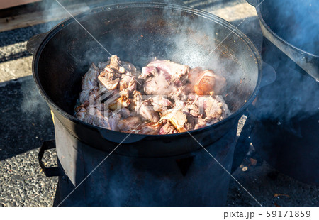 Pieces of meat cooking in a large cauldron 59171859