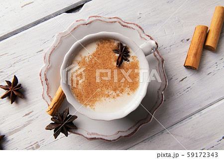 Beautiful cup of traditional indian masala chai tea on with star anise and cinnamon on a shabby wooden texture background. Beautiful cup of traditional indian masala chai tea on with star anise and cinnamon on a shabby wooden texture background. 59172343