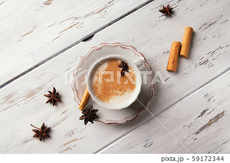 Beautiful cup of traditional indian masala chai tea on with star anise and cinnamon on a shabby wooden texture background. Beautiful cup of traditional indian masala chai tea on with star anise and cinnamon on a shabby wooden texture background. 59172344