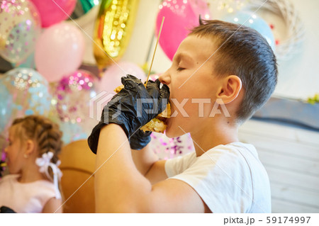 The handsome little boy eating burger in black rubber gloves. The handsome little boy eating burger in black rubber gloves. 59174997