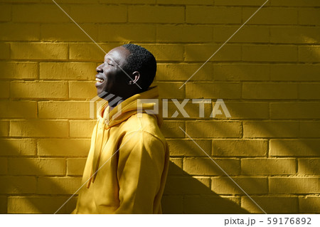 African Young Man Smiling With Yellow Wall In Background African Young Man Smiling With Yellow Wall In Background 59176892