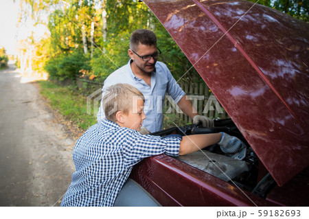 Father teaching his son how to check the oil on the family car. Father teaching his son how to check the oil on the family car. 59182693