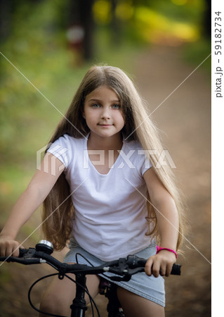 Little girl having fun on bike in the forest in autumn season 59182734