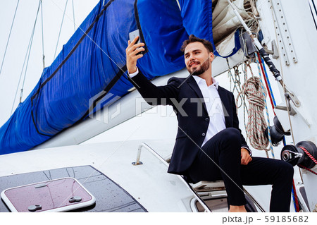 Man talking selfie on phone sitting on yacht Man talking selfie on phone sitting on yacht 59185682