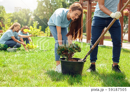 Volunteering. Young people volunteers outdoors planting trees boy helping girl digging plant from 59187505