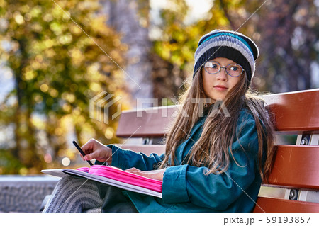 A teenager girl in glasses, a coat and a knitted 59193857
