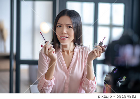 Young blogger having hesitations while choosing lipstick Young blogger having hesitations while choosing lipstick 59194882
