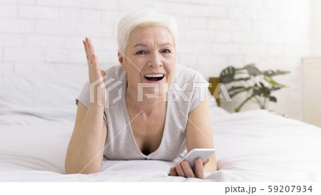 Excited senior woman enjoying win, reading message on smartphone 59207934
