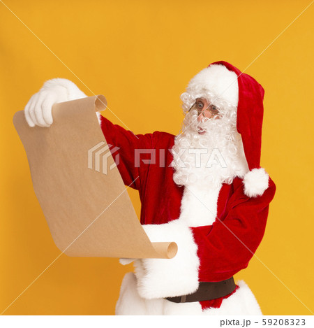 Santa Claus reading Christmas wishlist on orange background 59208323