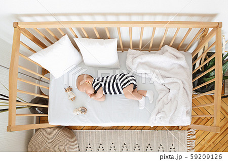 Lovely newborn baby sleeping on his side in wooden crib Lovely newborn baby sleeping on his side in wooden crib 59209126