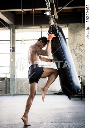 Boxers are training their knees with punching bag. 59209462