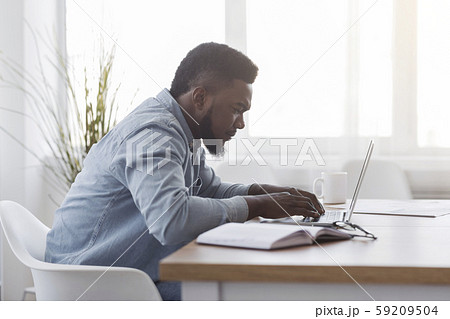 Concentrated african american manager working on laptop in office Concentrated african american manager working on laptop in office 59209504