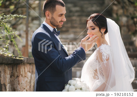Beautiful bride with her handsome groom walking outside on theri wedding day. Happy newlyweds Beautiful bride with her handsome groom walking outside on theri wedding day. Happy newlyweds 59210152