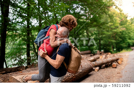 Senior tourist couple with backpacks walking in forest in nature. Senior tourist couple with backpacks walking in forest in nature. 59211092