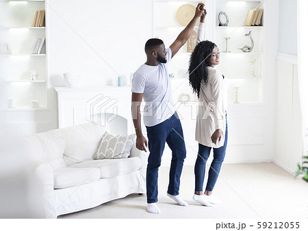 Romantic african american couple dancing at home, holding hands 59212055