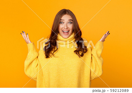 Excited woman raising hands in happiness, yellow background 59212089