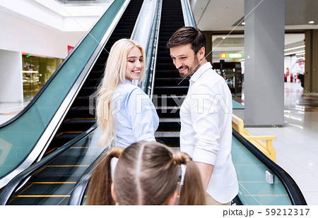 Parents And Daughter Standing On Escalator In Shopping Center Parents And Daughter Standing On Escalator In Shopping Center 59212317