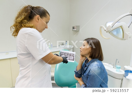 Dentist showing a patient her teeth x-ray. Healthcare, medical and dentistry concept Dentist showing a patient her teeth x-ray. Healthcare, medical and dentistry concept 59213557