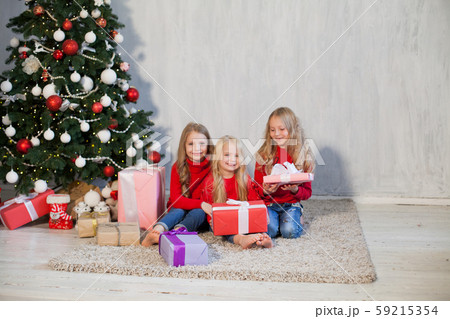 Three little girls open gifts at the Christmas tree new year winter Three little girls open gifts at the Christmas tree new year winter 59215354