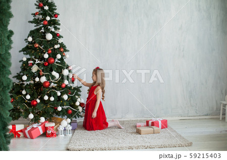 Little girl opens gifts at Christmas tree new year winter Little girl opens gifts at Christmas tree new year winter 59215403