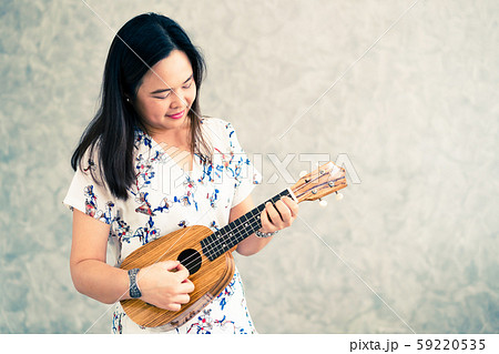 Happy woman musician playing ukulele in studio. 59220535
