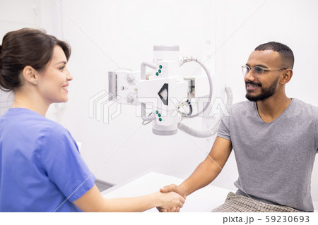 Happy young man shaking hand of his doctor or nurse after medical treatment Happy young man shaking hand of his doctor or nurse after medical treatment 59230693