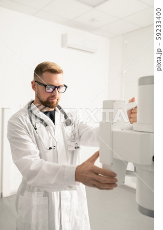 Bearded young man in whitecoat checking new medical equipment in clinics 59233400