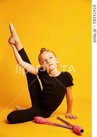 Little gymnast stretching leg near wands during training 59241419