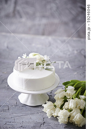 生クリームのホールケーキとthank Youのメッセージカード チューリップのブーケの写真素材