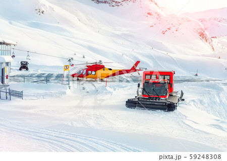 Mountain ski life rescue station with heavy machinery. Helicopter, snowcat and snowmobile standby 59248308