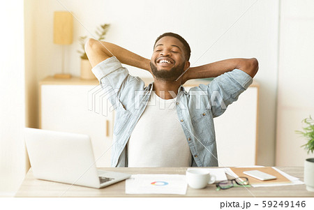 Happy afro worker leaning back in chair after successful workday 59249146