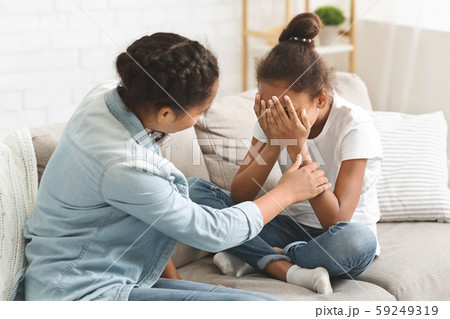 Teenaged girl comforting her crying little sister 59249319