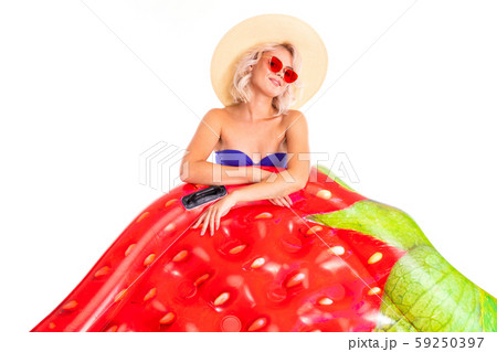 Pretty blonde caucasian female stands in swimsuit with rubber beach mattress and smiles isolated on Pretty blonde caucasian female stands in swimsuit with rubber beach mattress and smiles isolated on 59250397