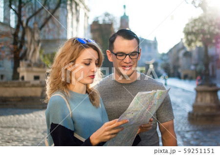 Tourists couple looking at the paper map and searching for direction early in the morning on empty 59251151