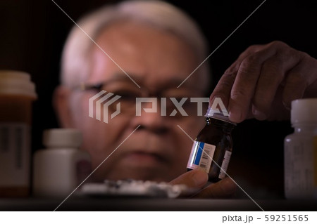 Senior man reading drug prescription on drug bottle 59251565