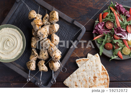 Grilled chicken skewers with hummus and salad Grilled chicken skewers with hummus and salad 59252072