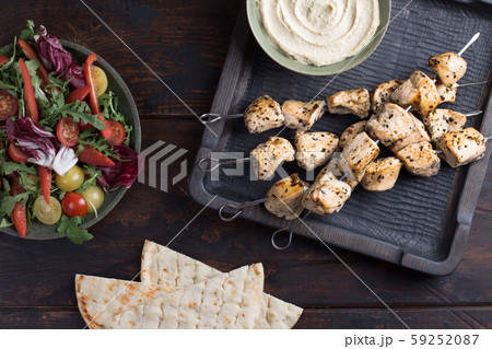 Grilled chicken skewers with hummus and salad 59252087