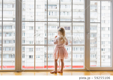 Happy little girl wearing cute dress looking at window 59255106